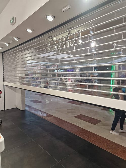 Fermeture d’un rideau métallique transparent dans un magasin KIKO rénové à Toulouse, offrant sécurité et visibilité en galerie marchande